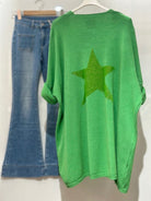 Green sweater with a star design and blue jeans on a white background