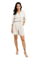 Woman wearing a light-colored outfit with shorts against a light green background