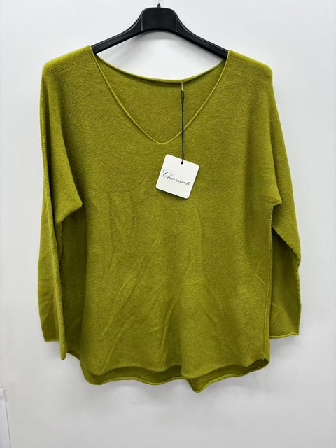 Green sweater on a hanger with a visible tag against a white background