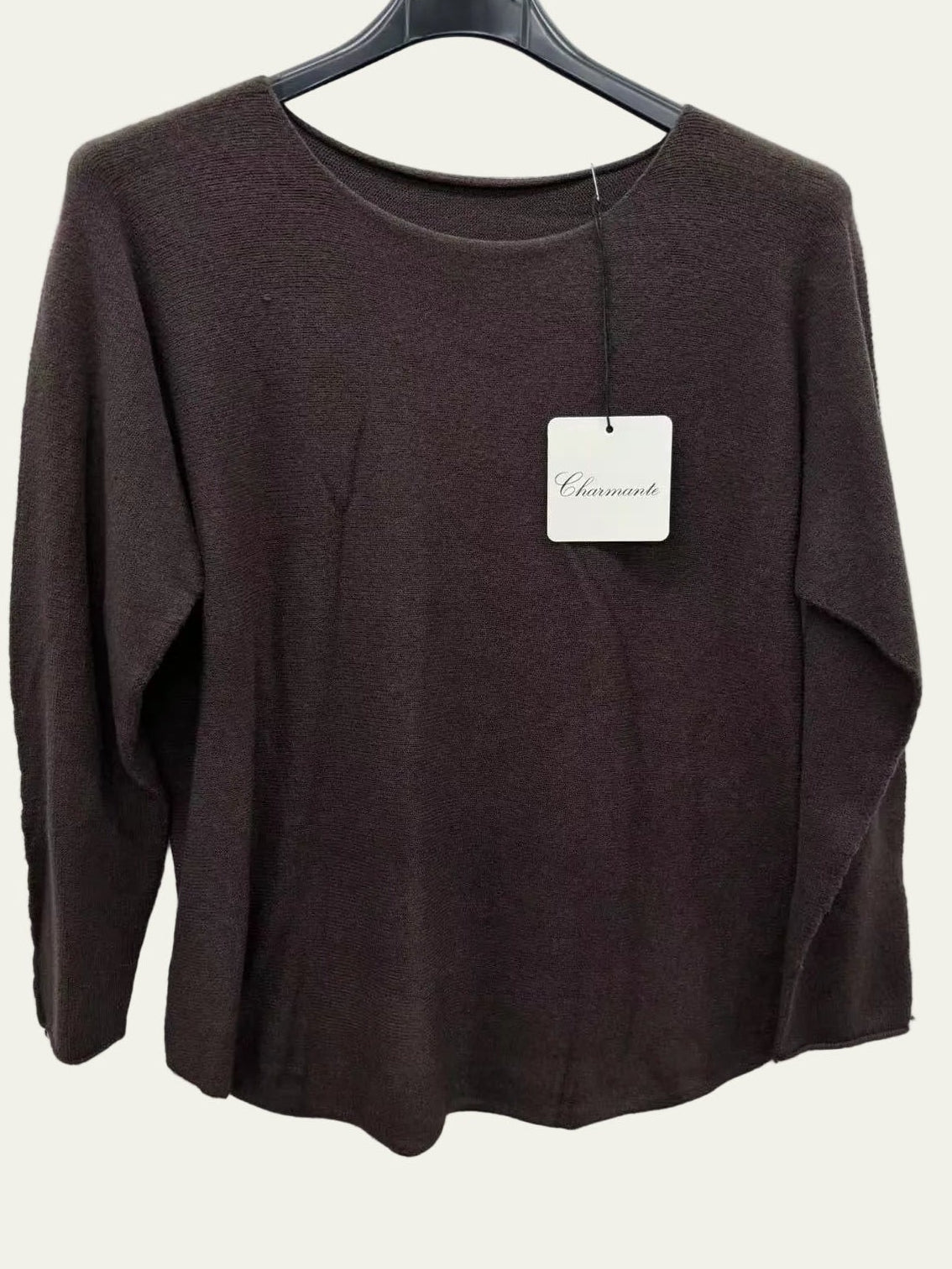 Brown sweater on a hanger with a visible tag against a white background