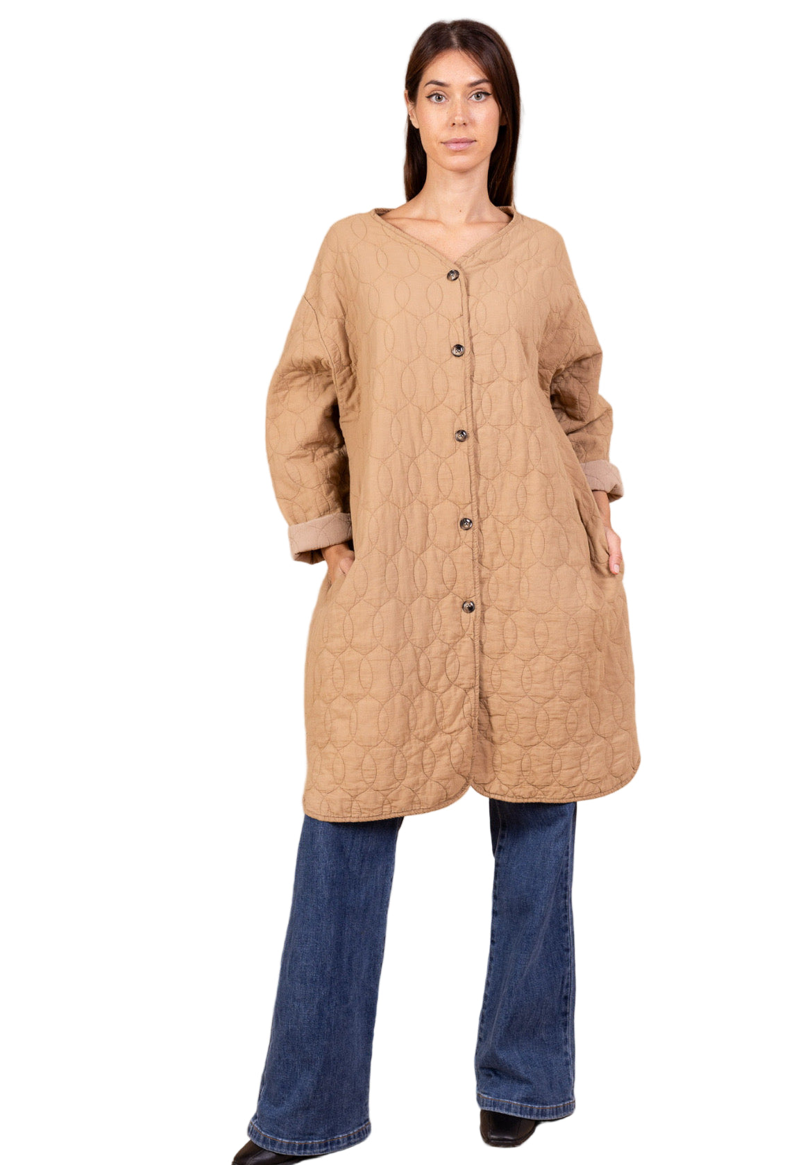 Woman wearing a beige quilted coat and blue jeans on a beige background