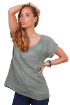 A person wearing a khaki v-neck cap sleeve top with a loose fit.