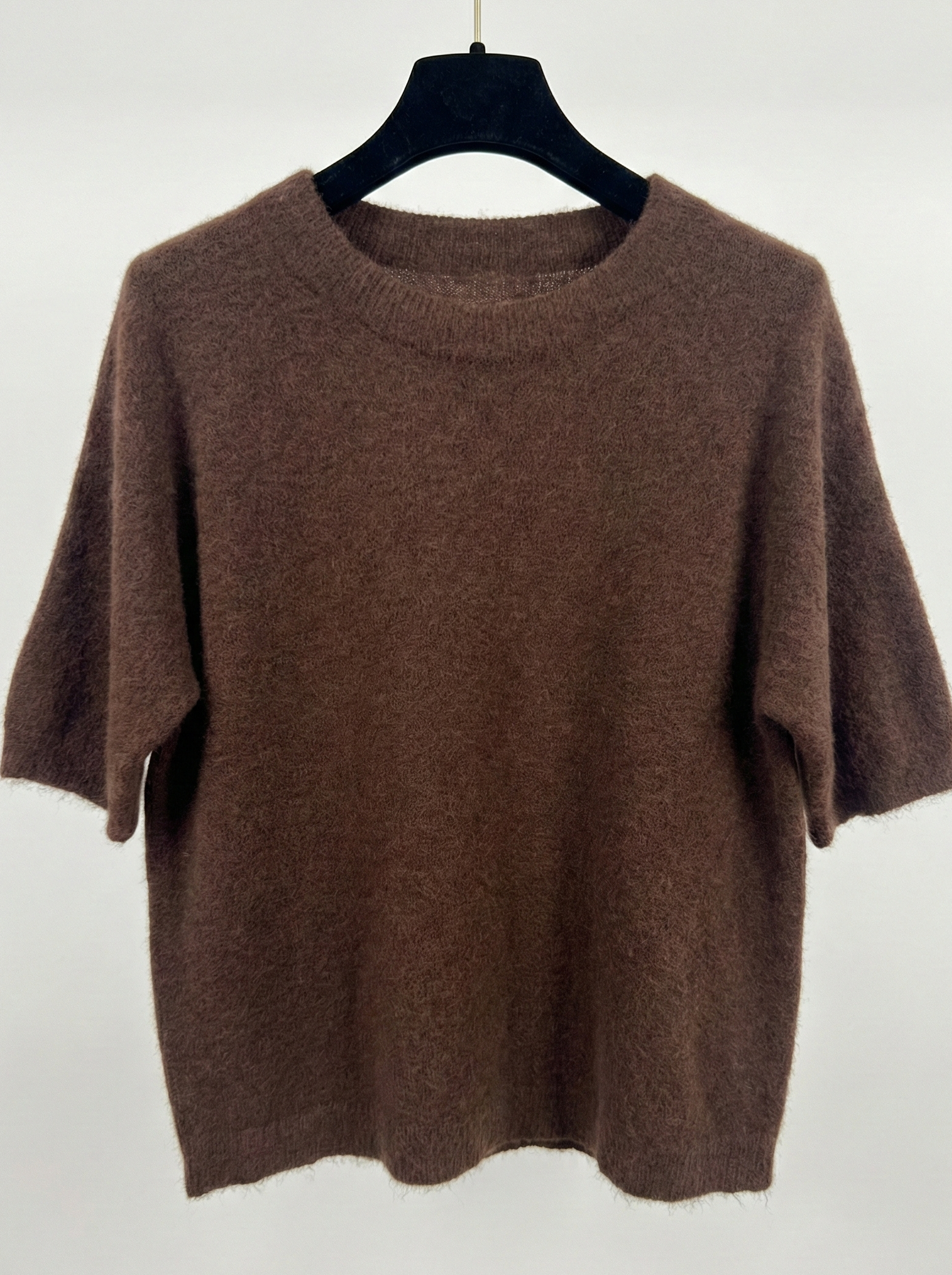 Brown sweater on a hanger against a white background