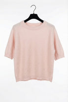 Pink t-shirt on a black hanger against a white background