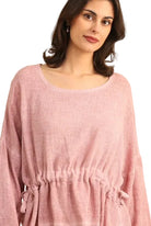 Woman wearing a pink linen tunic against a white background