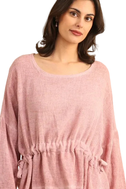Woman wearing a pink linen tunic against a white background