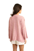 Woman wearing a pink linen tunic on a white background