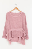 Pink tunic on a wooden hanger against a white background
