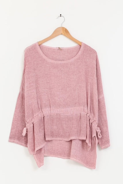 Pink tunic on a wooden hanger against a white background