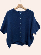 Blue cardigan on a hanger against a beige background
