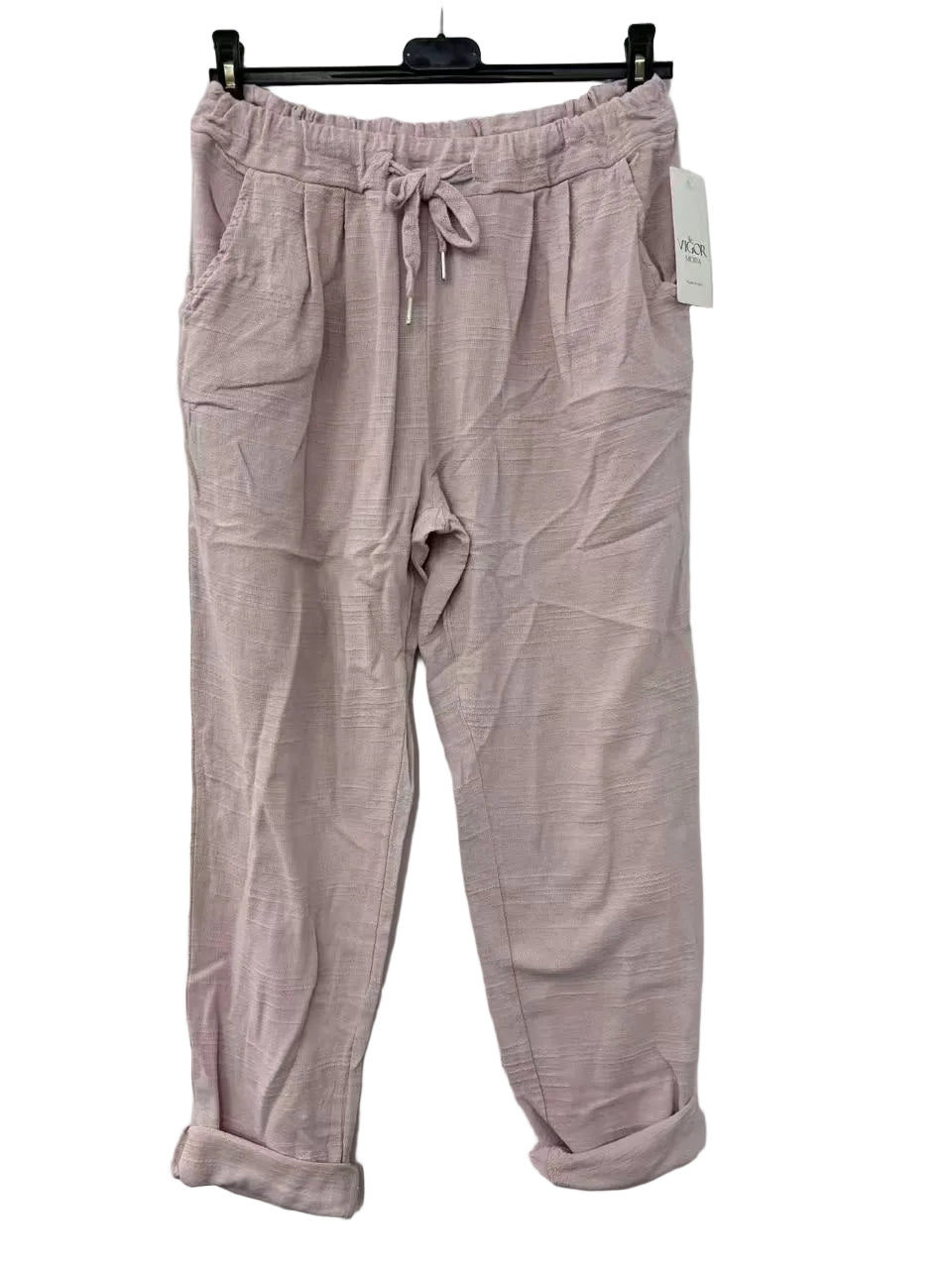Pink cotton pants on a hanger against a white wall