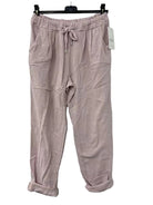 Pink cotton pants on a hanger against a white wall
