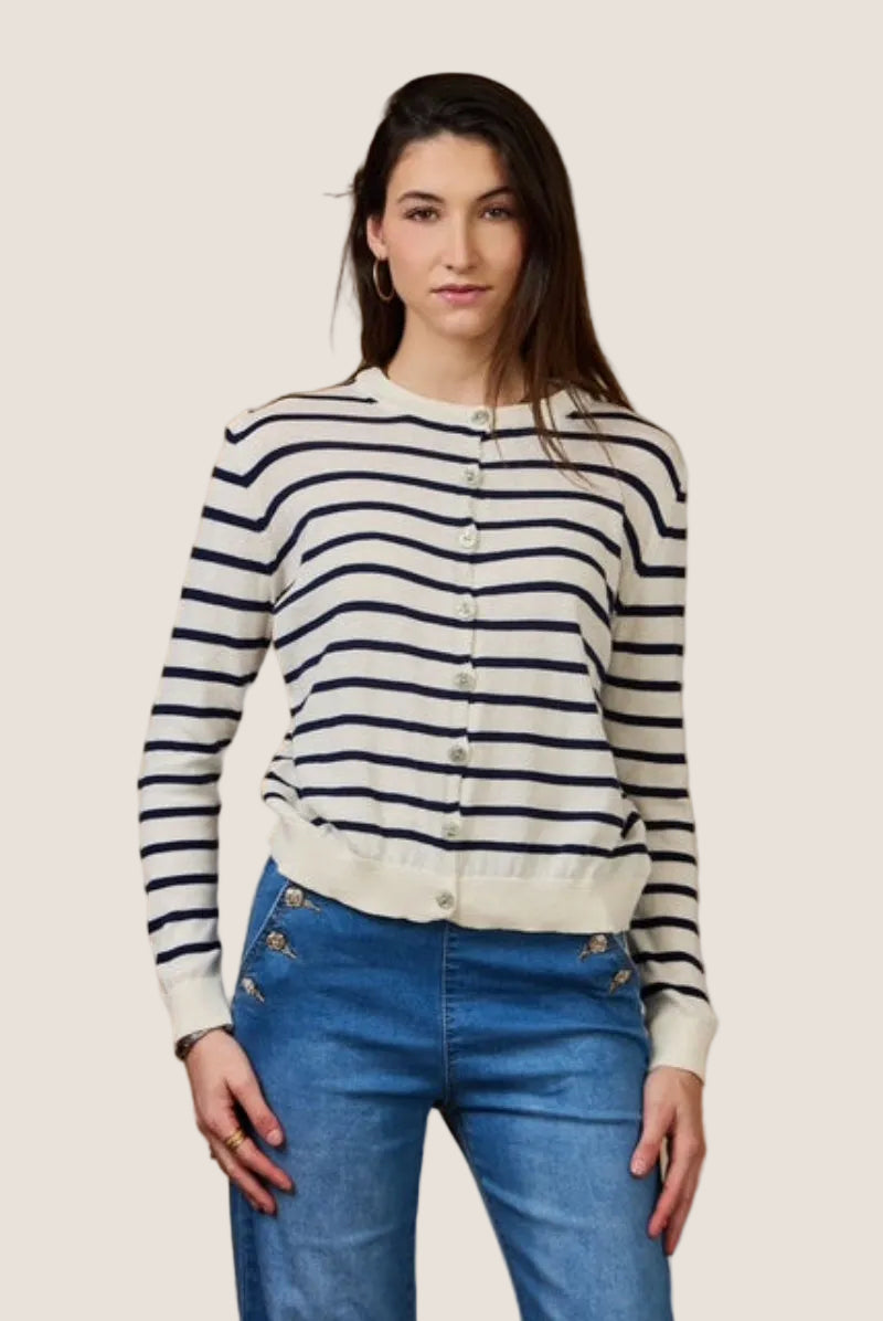 Woman wearing a striped cardigan and blue jeans against a beige background