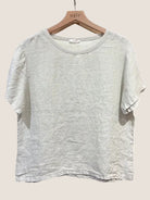 Beige t-shirt on a wooden hanger against a white background