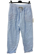 Sky Blue cotton gauze trousers on a hanger against a beige wall
