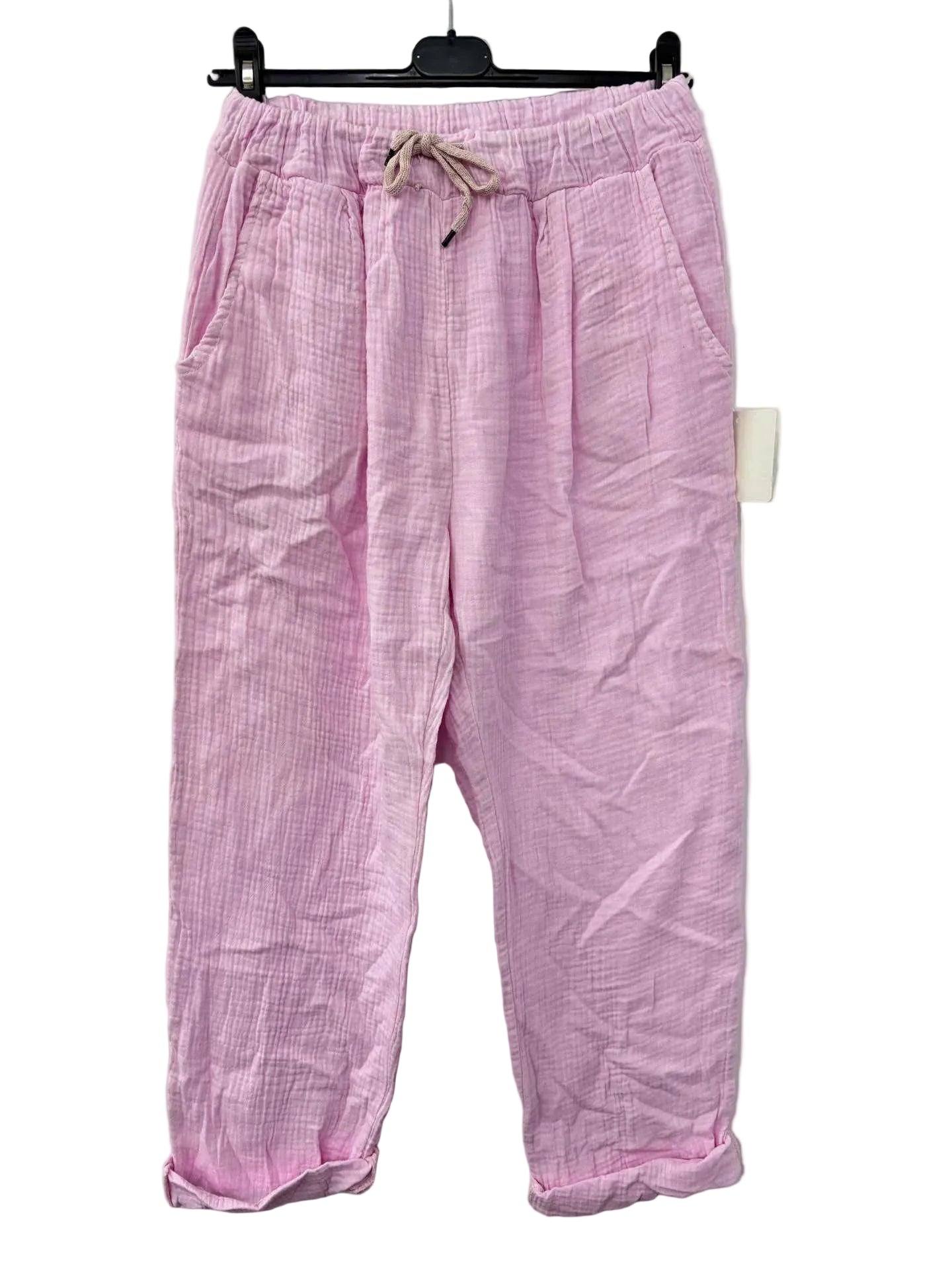 Pink cotton gauze trousers on a hanger against a white background