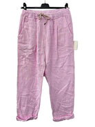 Pink cotton gauze trousers on a hanger against a white background