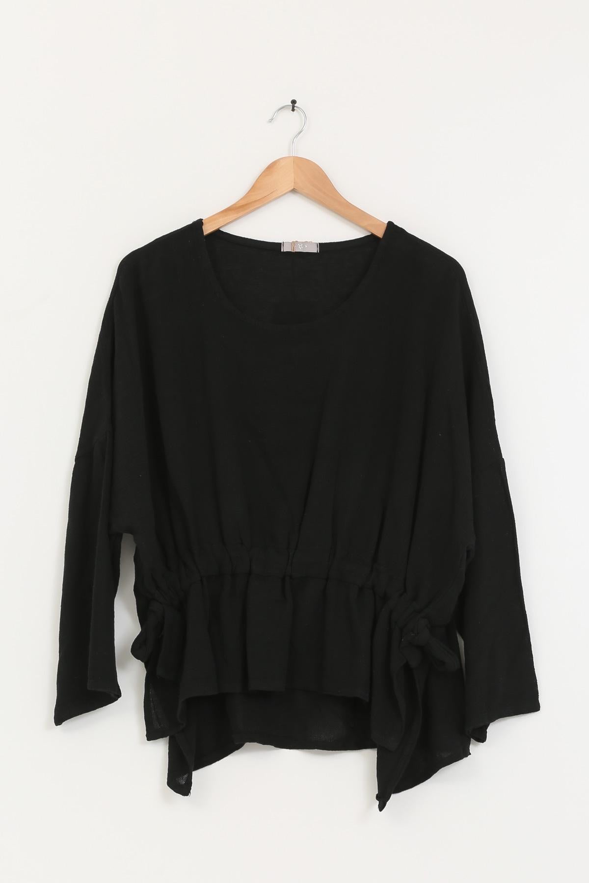 Black linen tunic on a wooden hanger against a white background