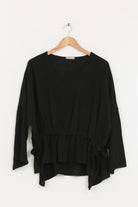 Black linen tunic on a wooden hanger against a white background