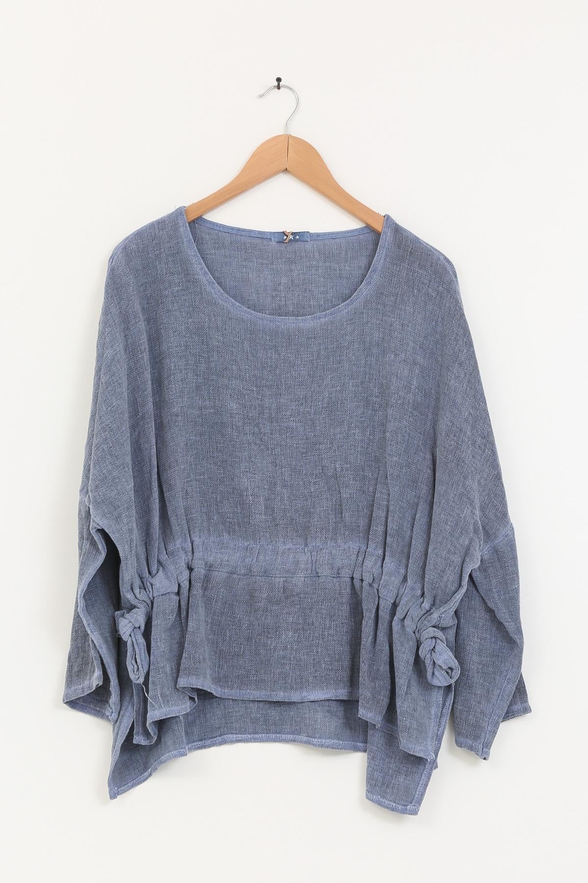 Blue linen tunic on a wooden hanger against a white background
