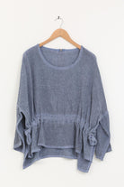 Blue linen tunic on a wooden hanger against a white background