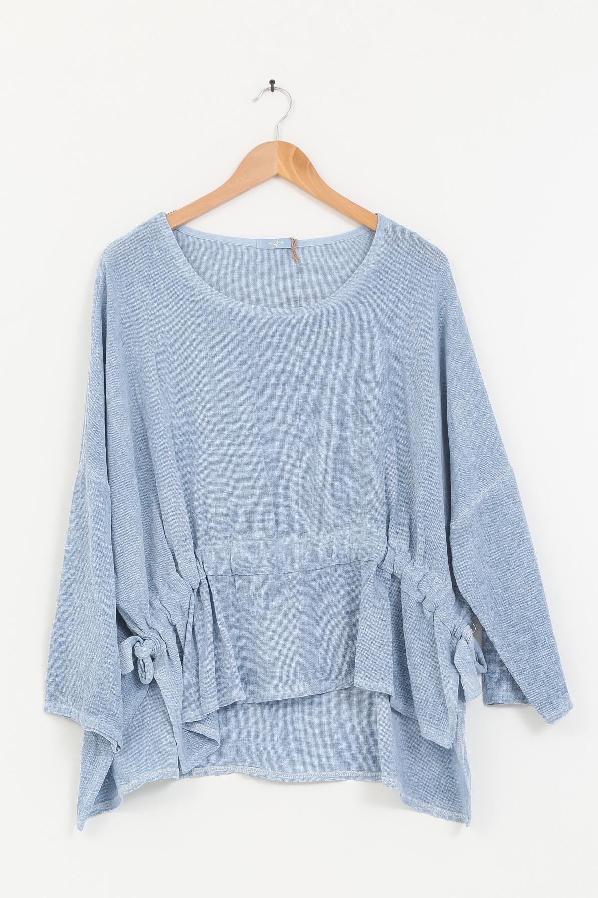 Blue jeans linen tunic on a wooden hanger against a white background
