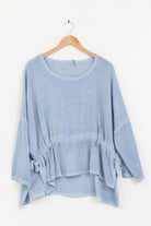 Blue jeans linen tunic on a wooden hanger against a white background