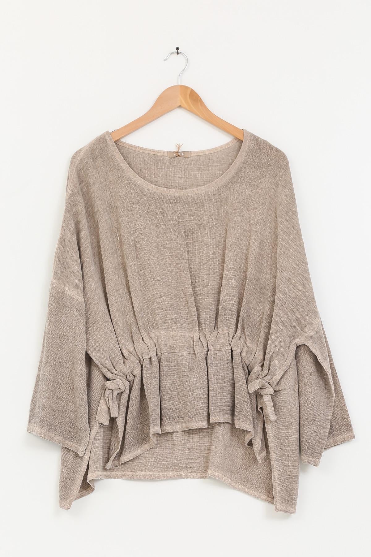 Beige linen tunic with tie details on a wooden hanger against a white background