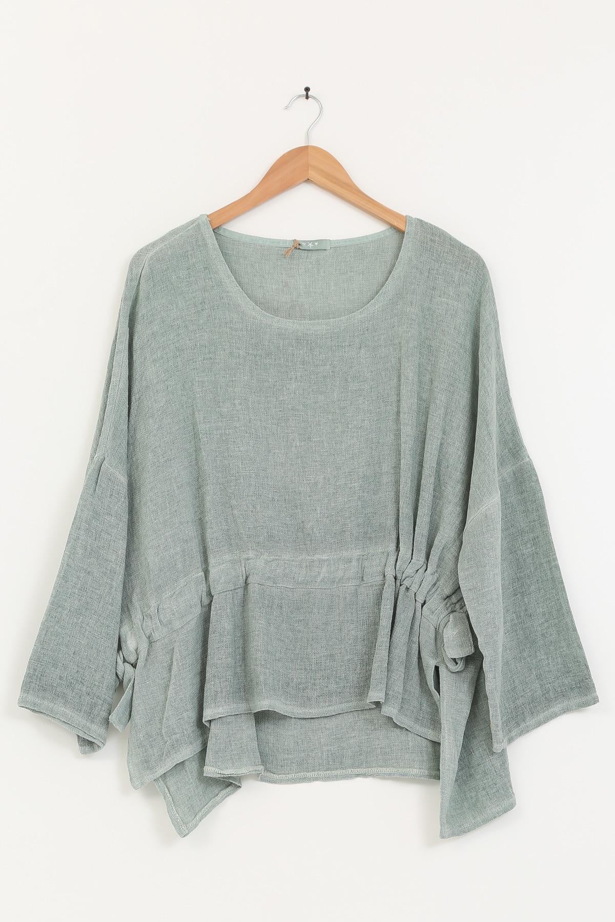 Duck green linen top on a wooden hanger against a white background