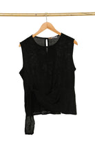 Black sleeveless top on a wooden hanger against a white background