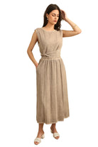 Woman in a taupe linen top & skirt with white background