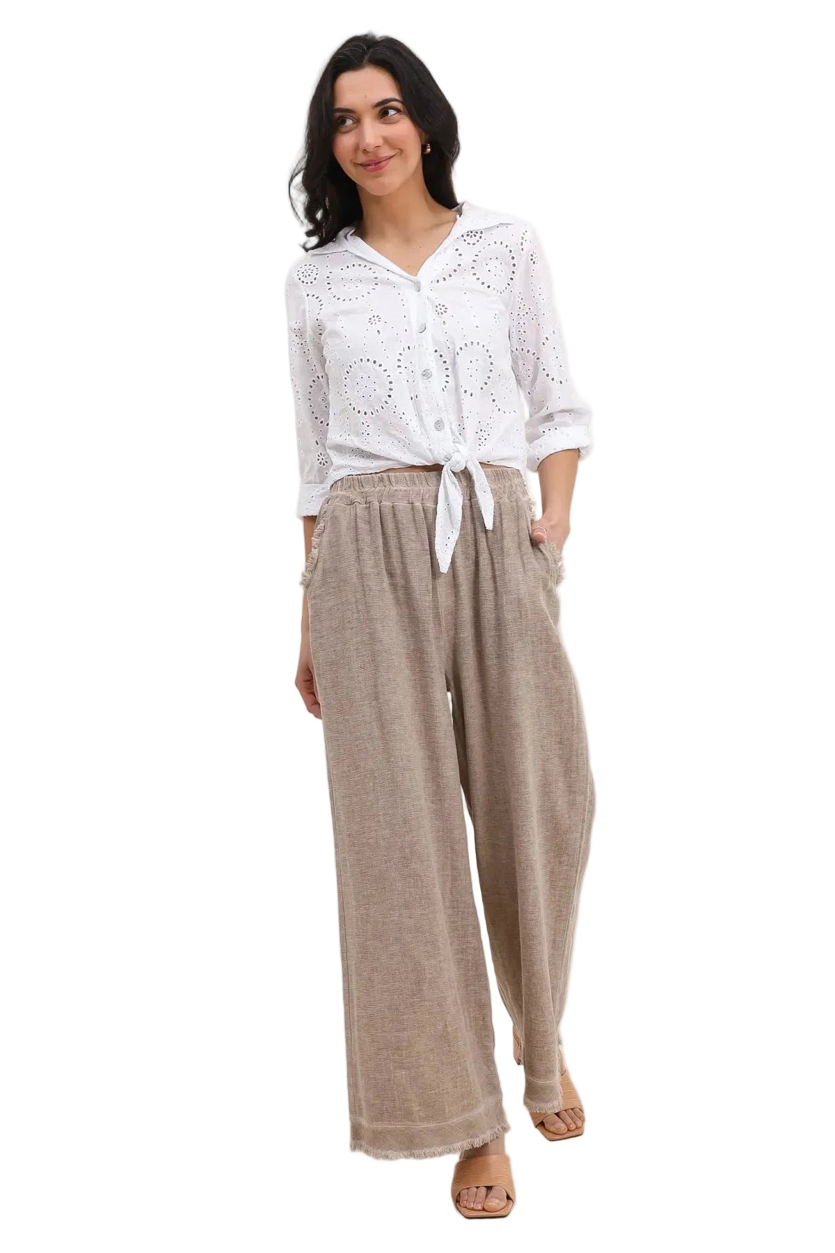 Woman wearing a white blouse and taupe pants on a white background