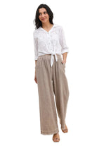 Woman wearing a white blouse and taupe pants on a white background