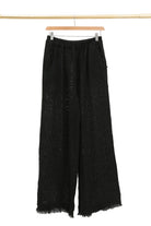 Black wide-leg pants on a hanger against a white background
