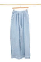 Light blue denim wide-leg pants on a hanger against a white background