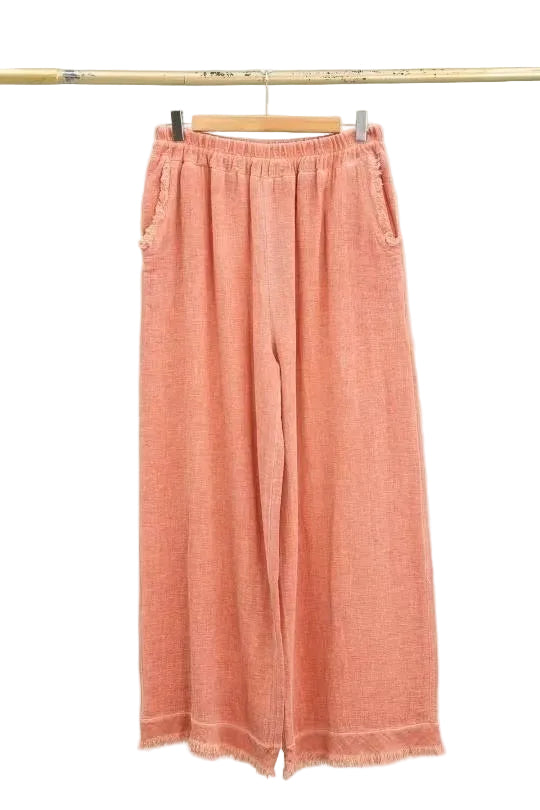 Orange pants hanging on a rack against a white background
