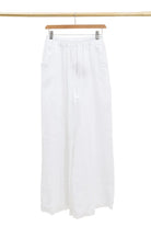 White pants hanging on a wooden hanger against a white background