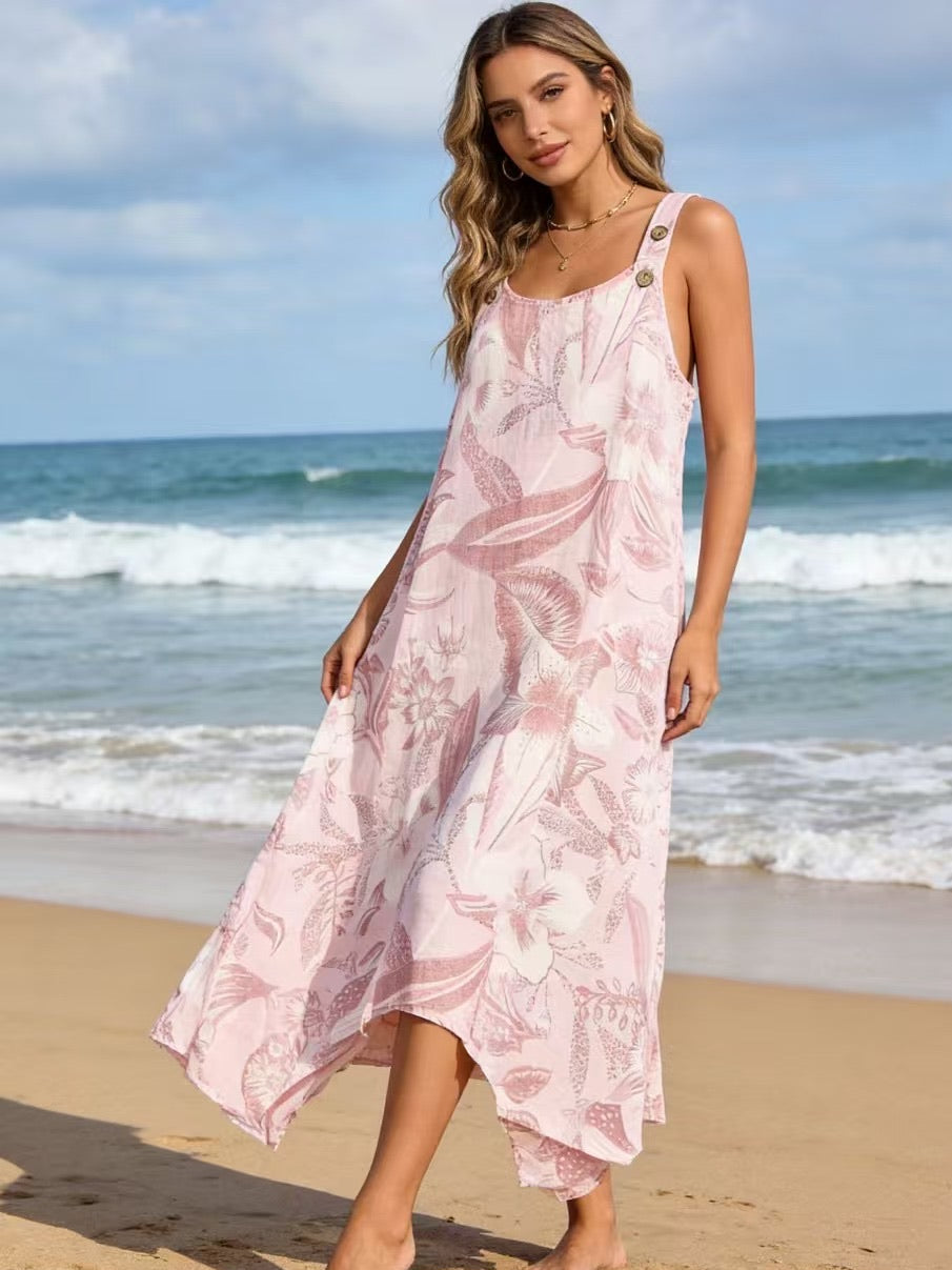 Woman in a pink floral dress standing on a beach with ocean waves in the background