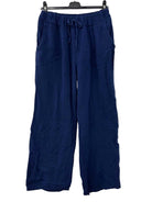 Navy blue pants hanging on a rack against a white wall