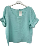 Turquoise textured top on a hanger against a white background
