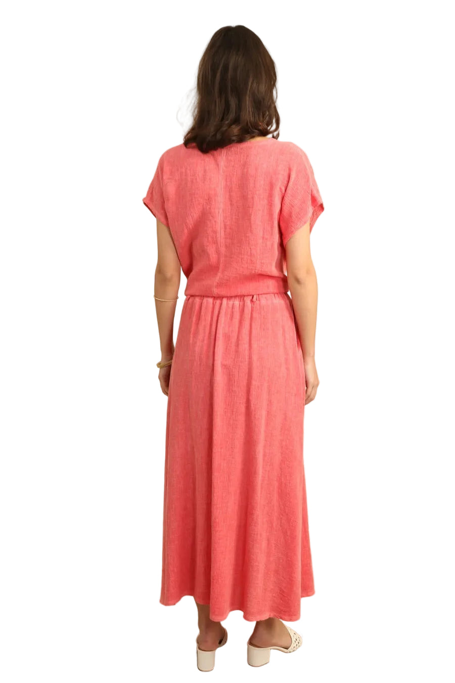 Woman wearing a coral top & skirt standing against a white background 