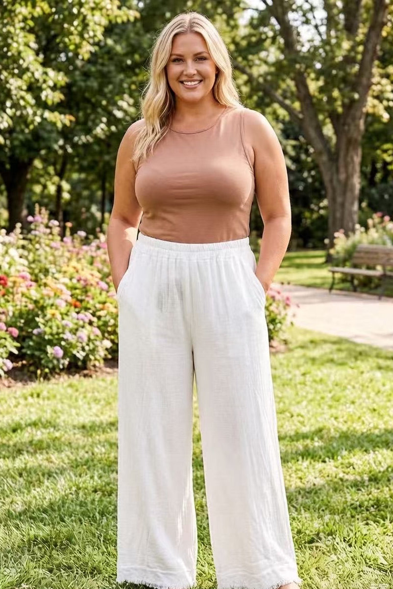 Woman wearing a brown top and white pants standing in a park.