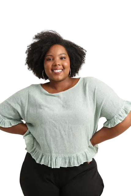 Woman wearing a light green blouse with ruffled sleeves on a white background