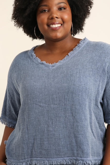 Woman wearing a blue denim top with a plain background