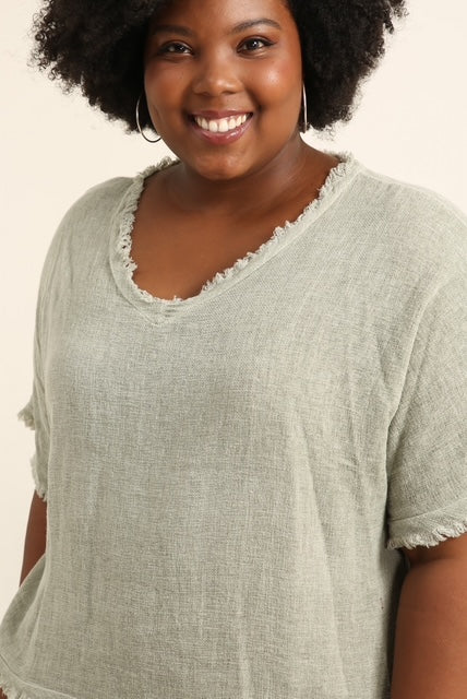 Woman wearing a duck green top with a plain background