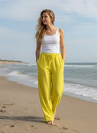 Yellow cotton trousers, white t shirt with beach background.