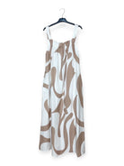 White dress with brown abstract pattern on a hanger against a white background