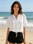 Woman wearing a white shirt and black shorts on a beach