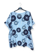 Blue shirt with black circular pattern on a hanger against a white background