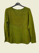 An olive green long-sleeve knit top with a V-neckline, hanging on a black hanger against a plain white wall.